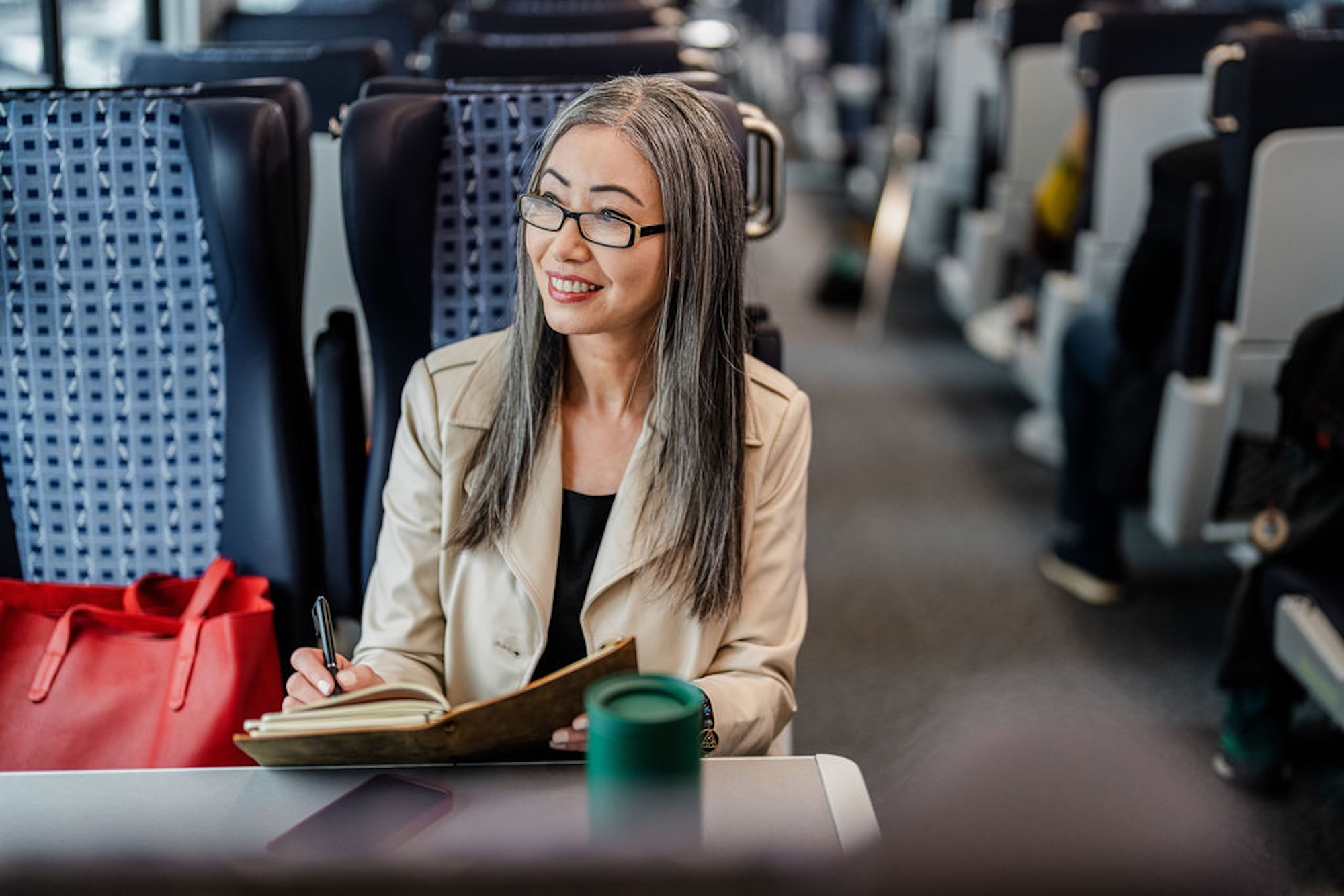 woman writing into notebook while on the train