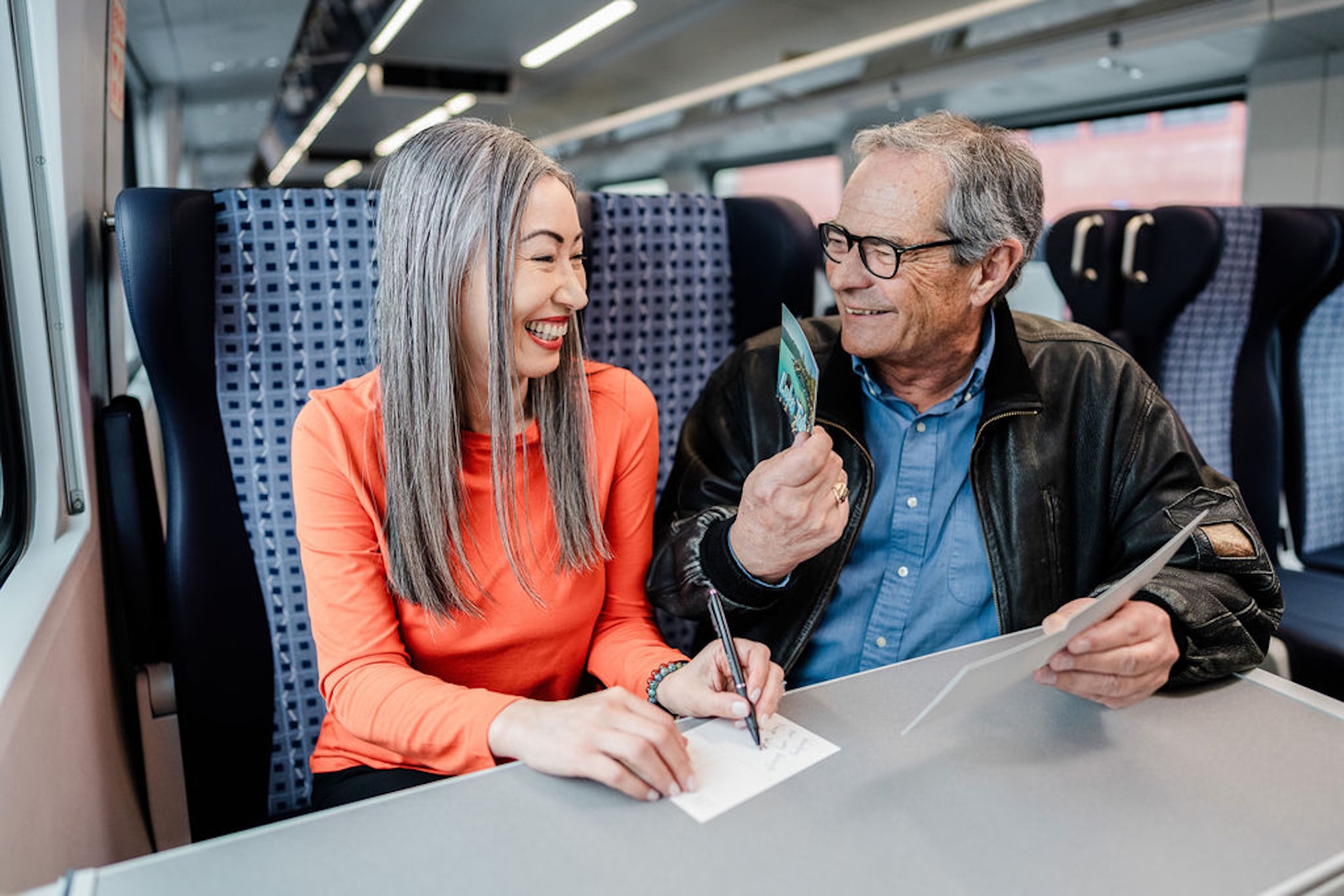older man and woman on train laughing with each other
